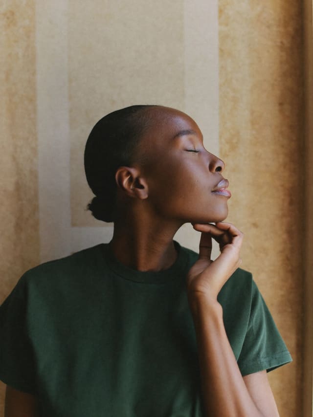 Model in profile in a green T-shirt, eyes closed, hand at chin